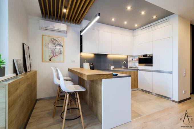 Virtuvė ir valgomasis balta spalvos su medienos akcentais.